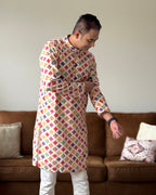 Person wearing a colorful patterned kurta standing in a living room.