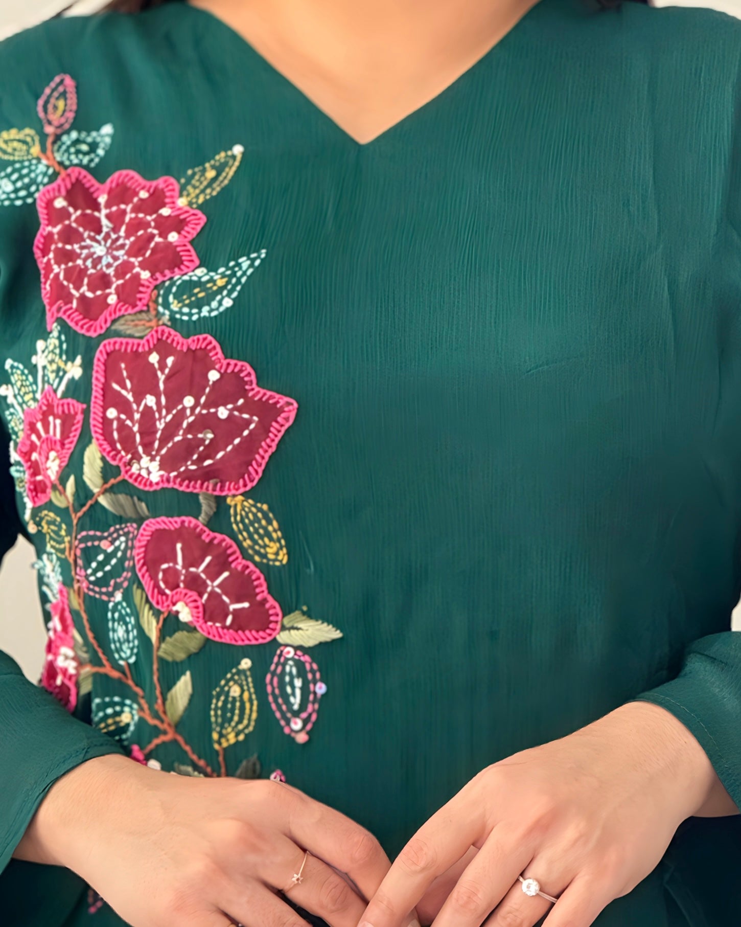 Green garment with floral embroidery on a plain background
