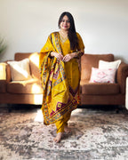 Woman in a yellow saree with a pattern standing in a living room.