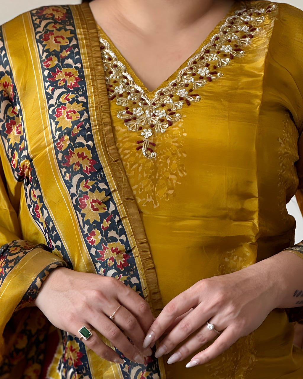 Close-up of a person wearing a yellow embroidered traditional outfit with floral patterns.