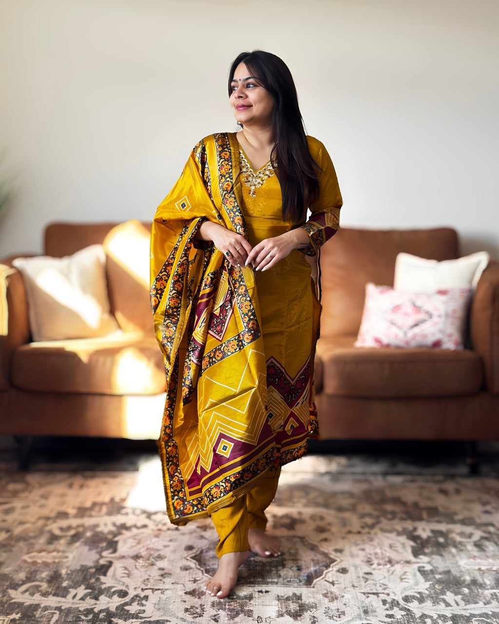 Woman in a yellow traditional outfit standing in a living room.