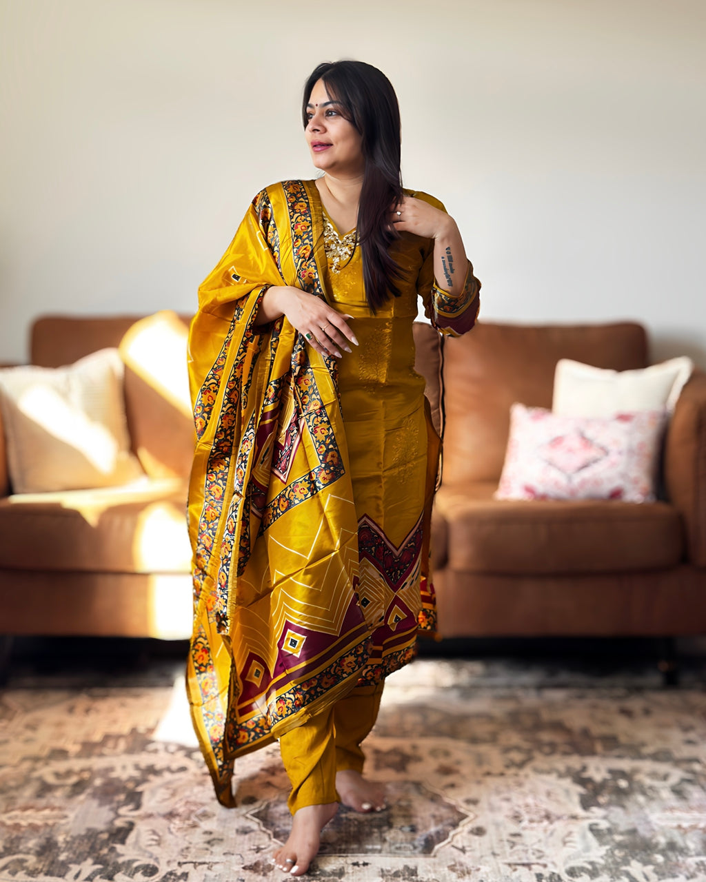 Woman in a yellow traditional outfit standing in a living room.