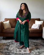 Woman in a green traditional outfit standing in a living room.