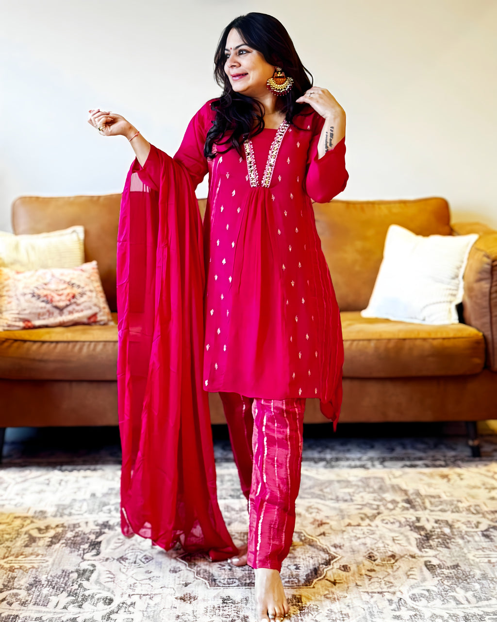 Woman in a red traditional outfit standing in a living room.