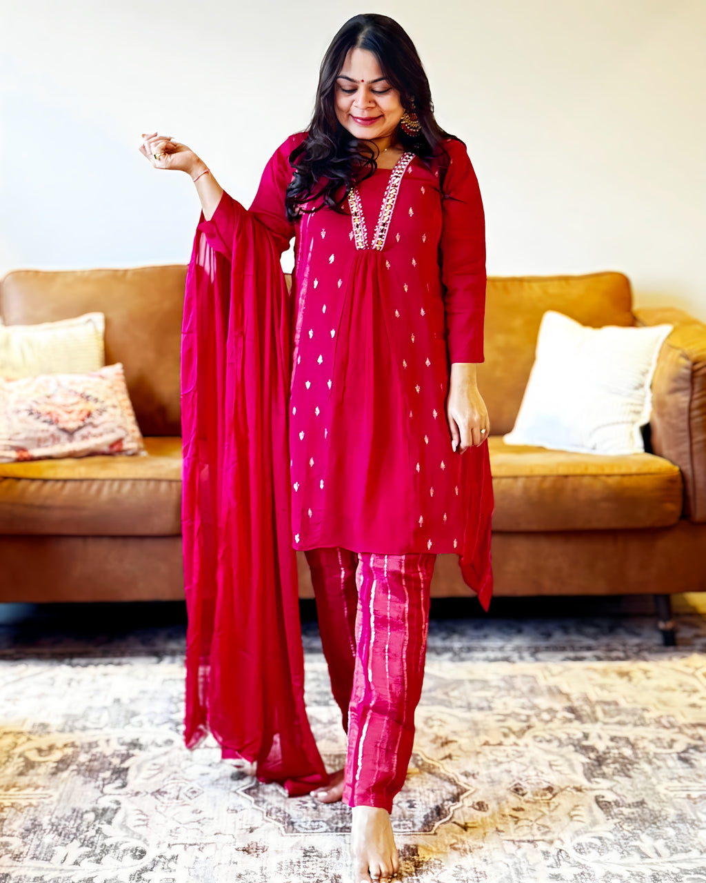 Woman in a red traditional outfit standing in a living room.