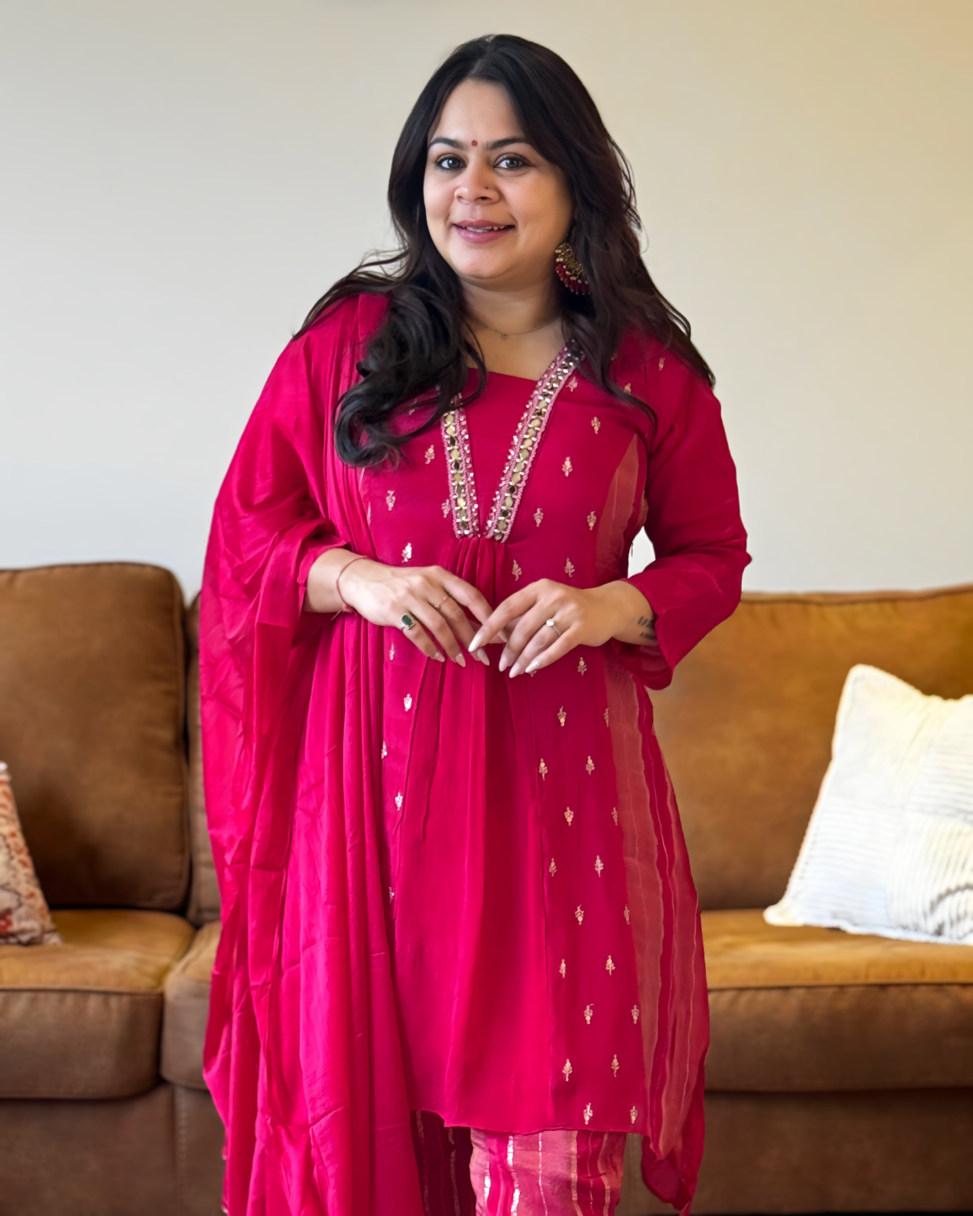 Woman in a red traditional outfit standing in a living room.