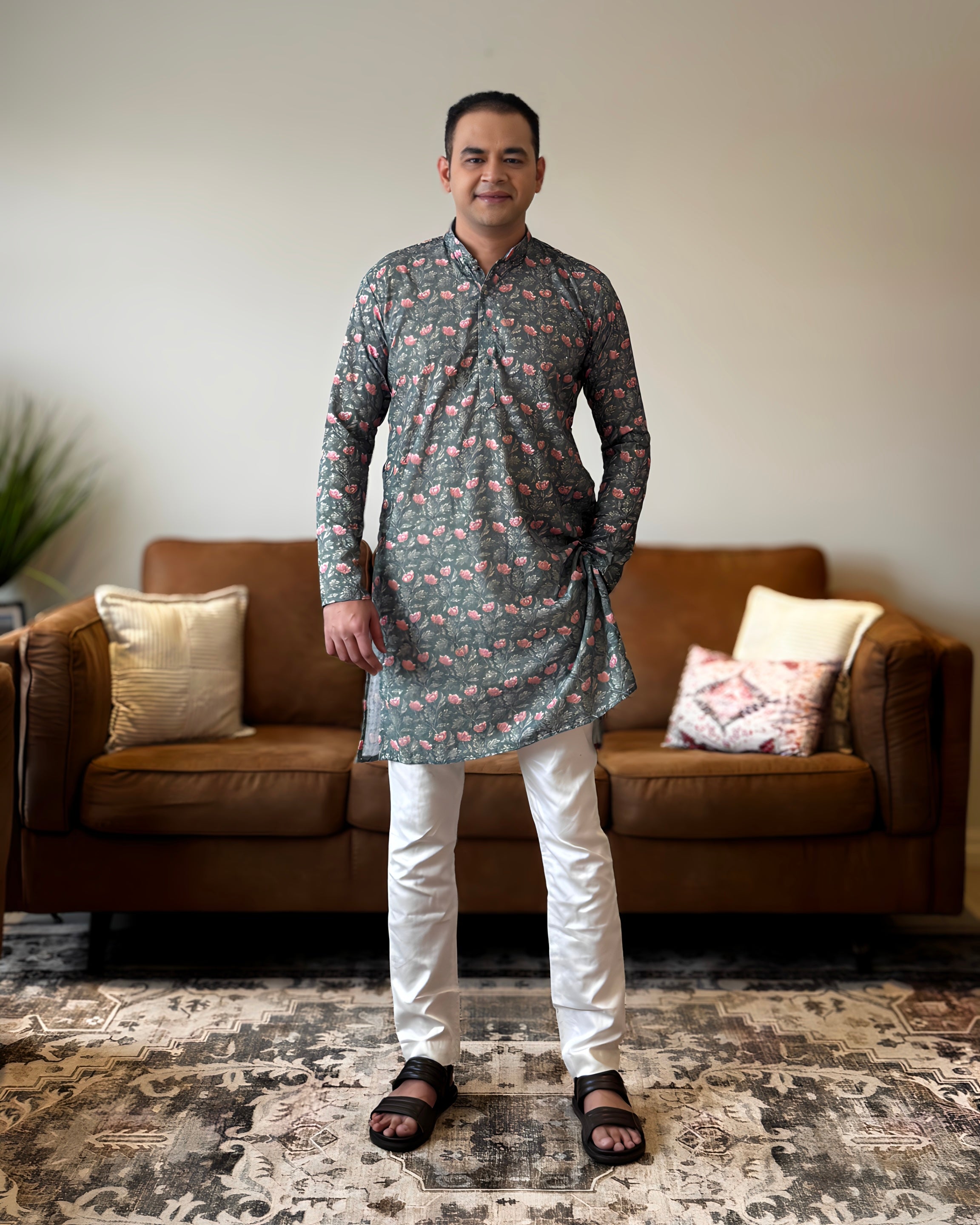 Man wearing a floral kurta and white pants standing in a living room.