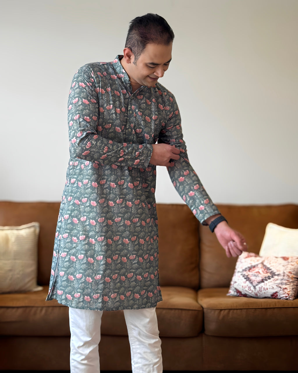Man wearing a patterned kurta standing in a living room.