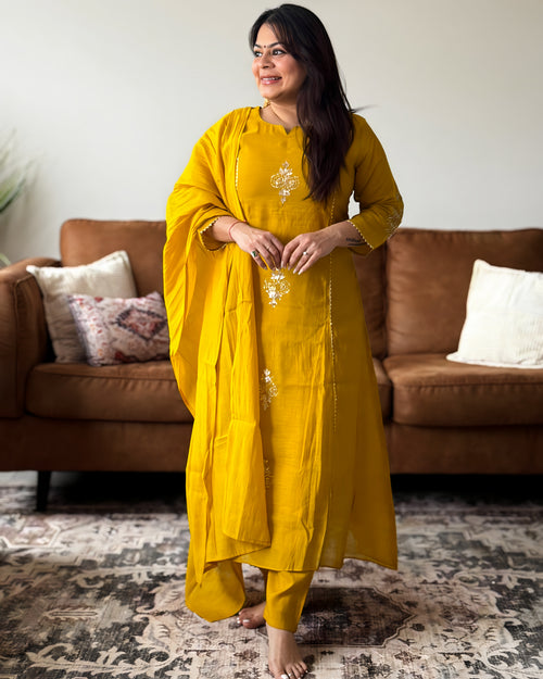 Woman in a yellow traditional outfit standing in a living room.