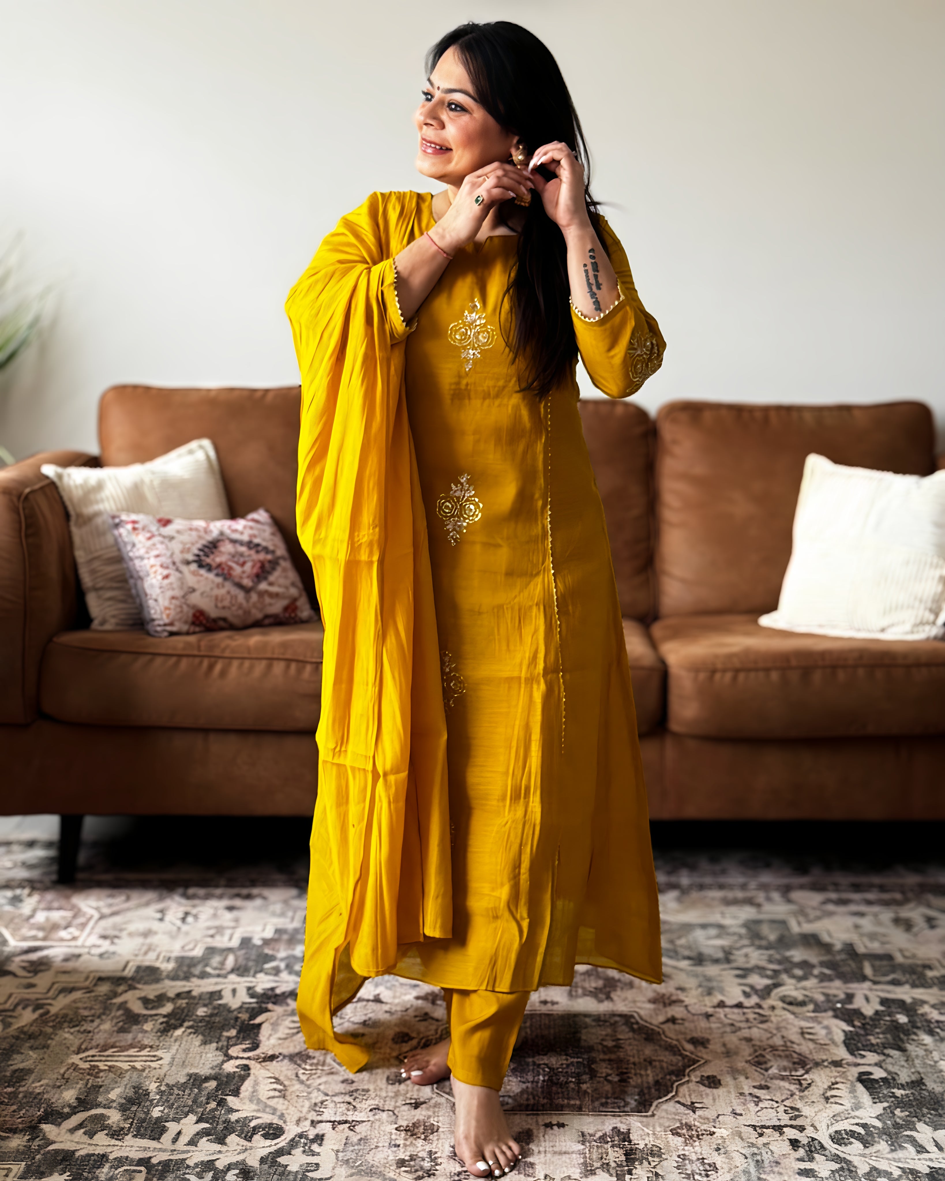 Woman in a yellow traditional outfit standing in a living room.