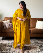 Woman in a yellow traditional outfit standing in a living room.