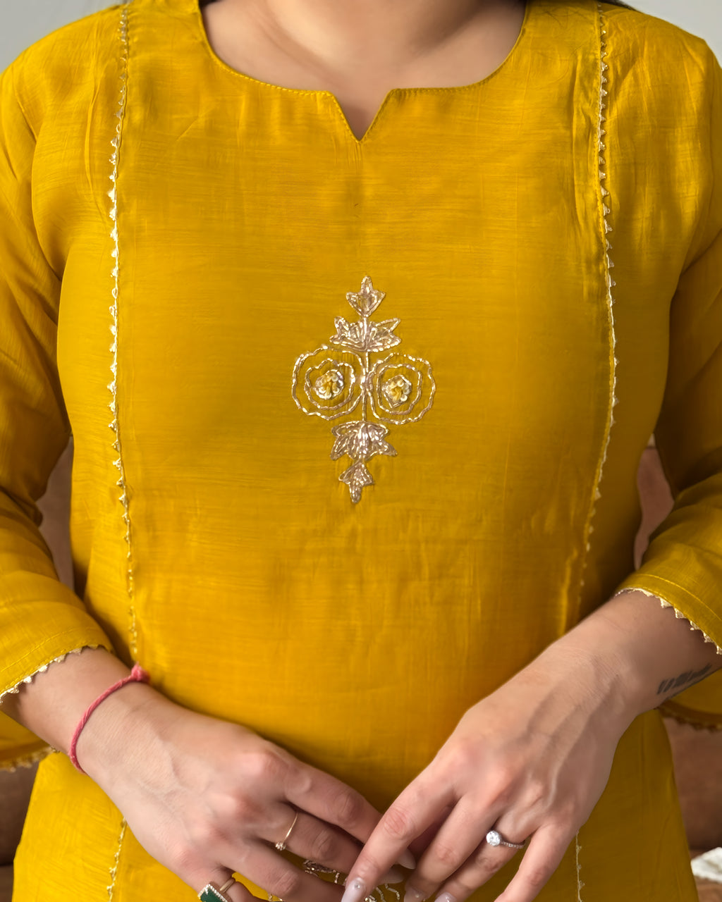 Yellow kurta with intricate silver embroidery on a plain background