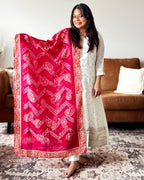 Woman holding a pink and white patterned scarf in a living room setting