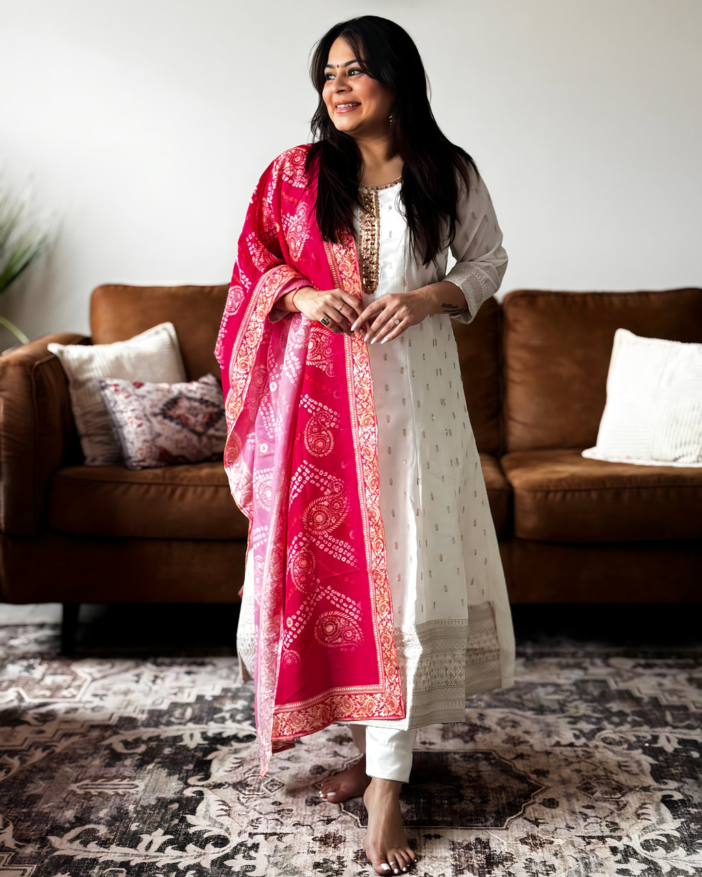 Woman wearing a white kurta with a pink dupatta in a living room setting