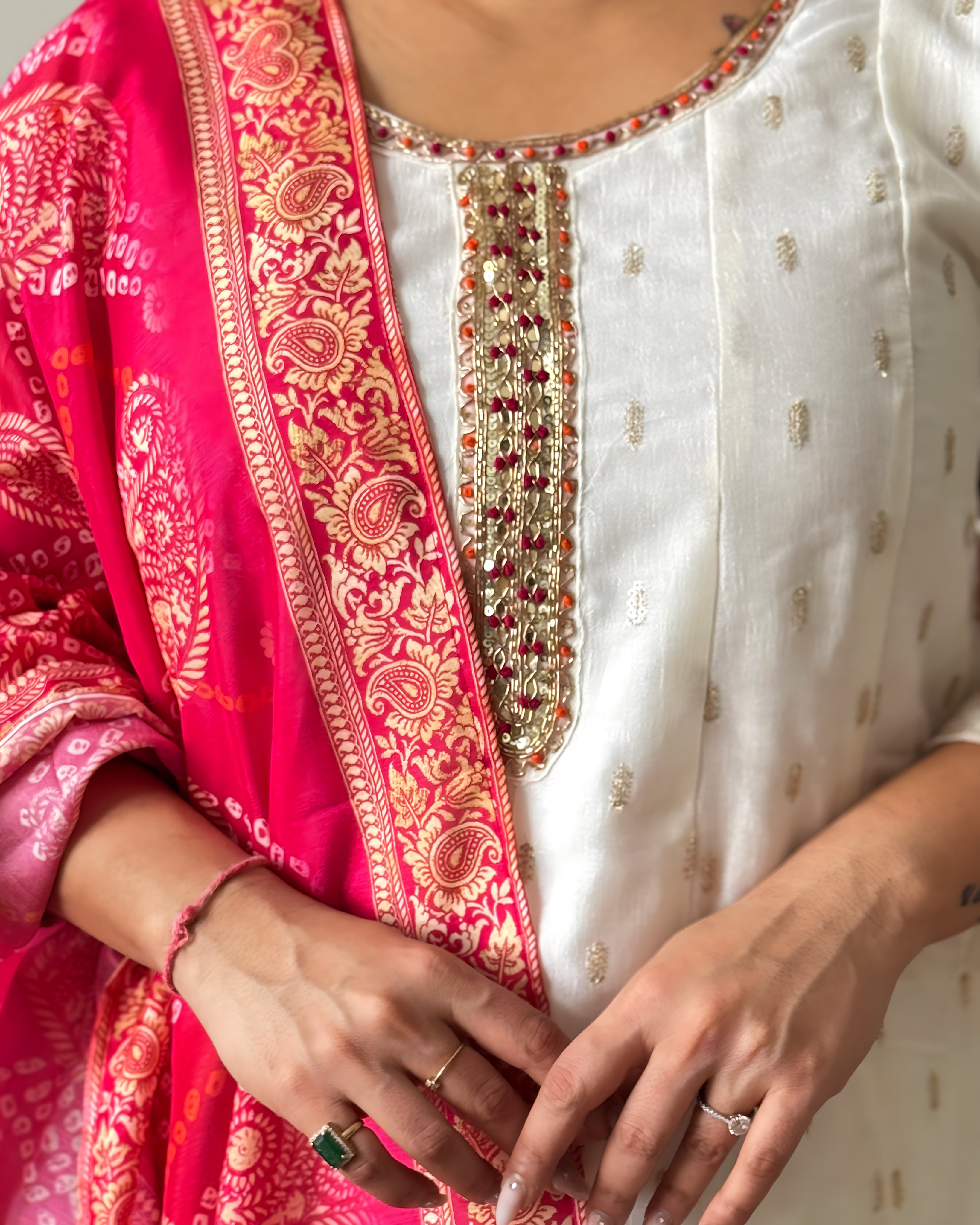 Close-up of a person wearing a white embroidered top with a red and gold border.