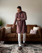 Man wearing a patterned kurta with white pants in a living room setting.