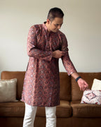 Man wearing a patterned kurta in a living room setting