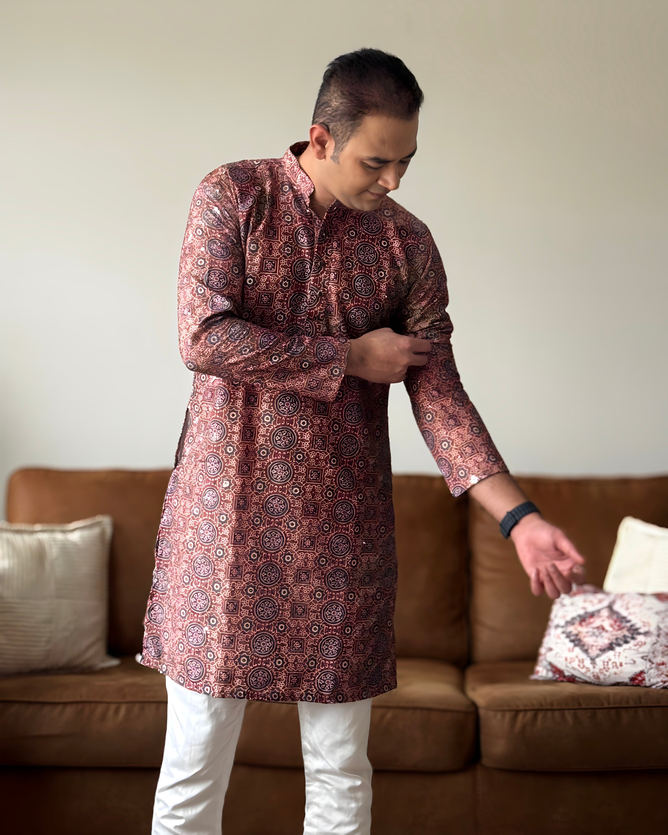 Man wearing a patterned kurta in a living room setting