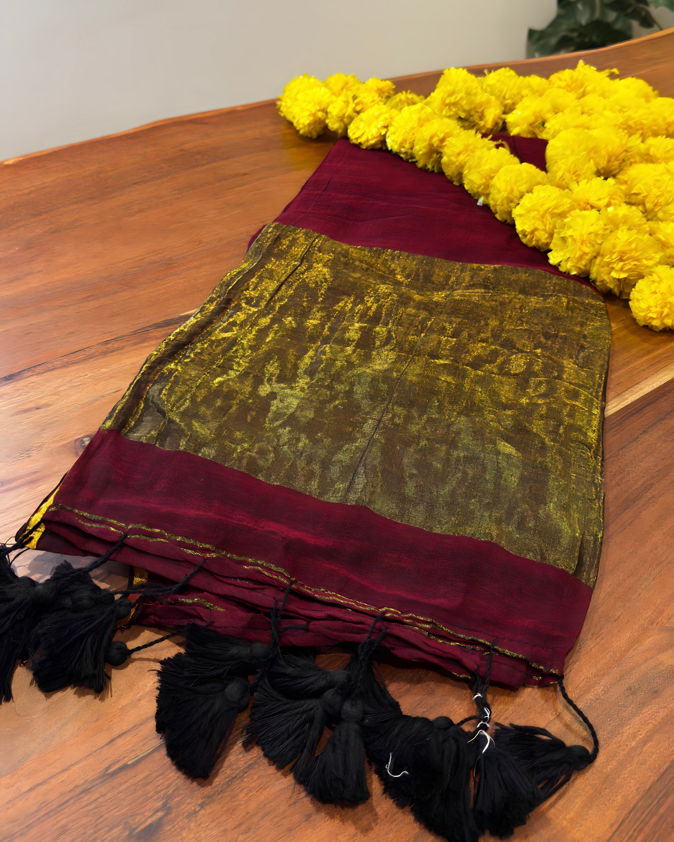 Green and red fabric with black tassels on a wooden surface