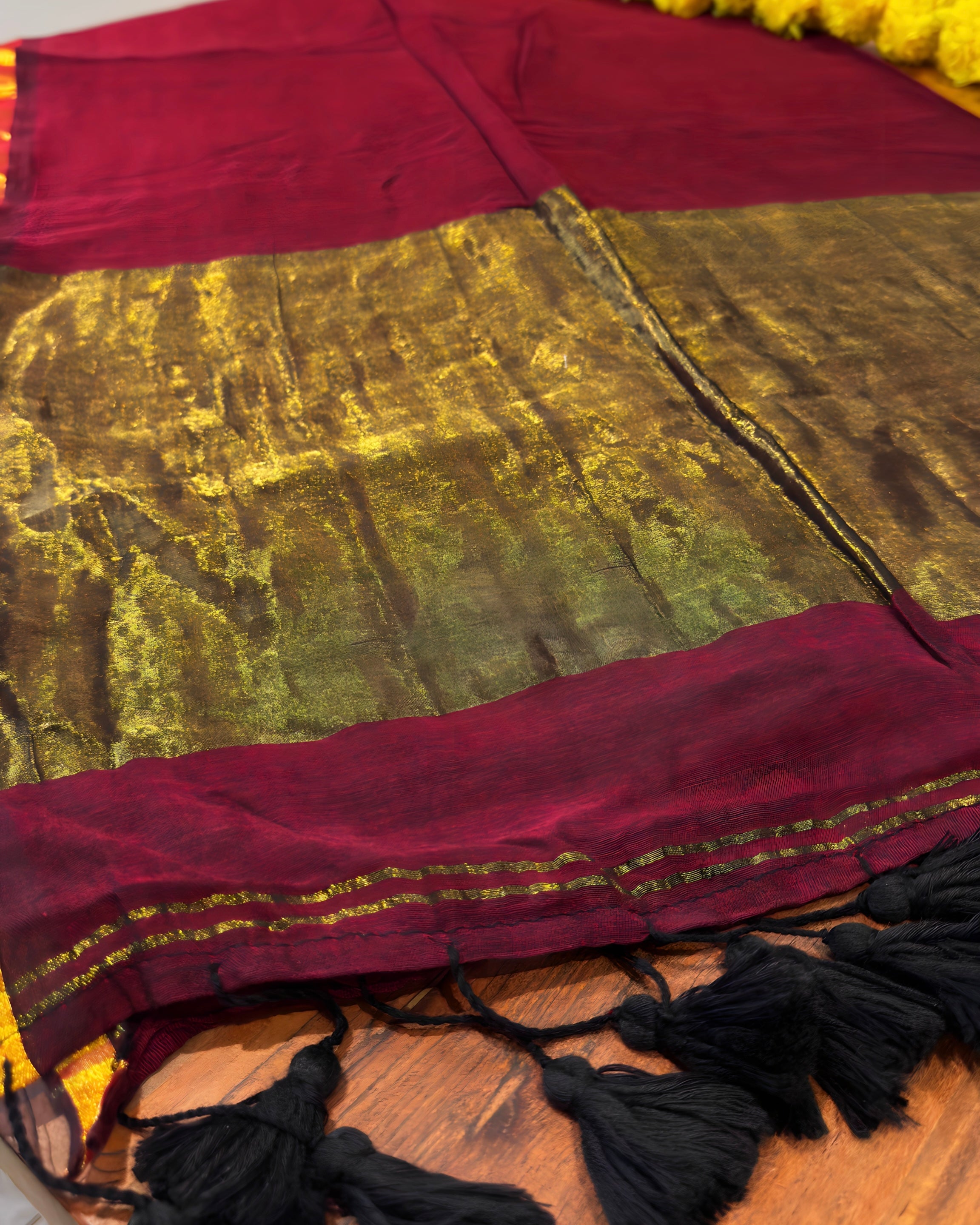 Close-up of a maroon and gold fabric with tassels on a wooden surface