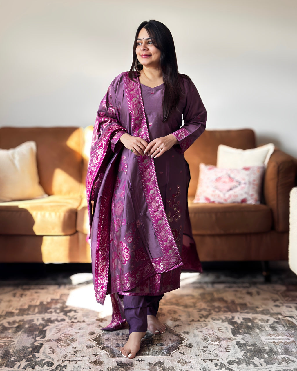 Woman in a purple traditional outfit standing in a living room.