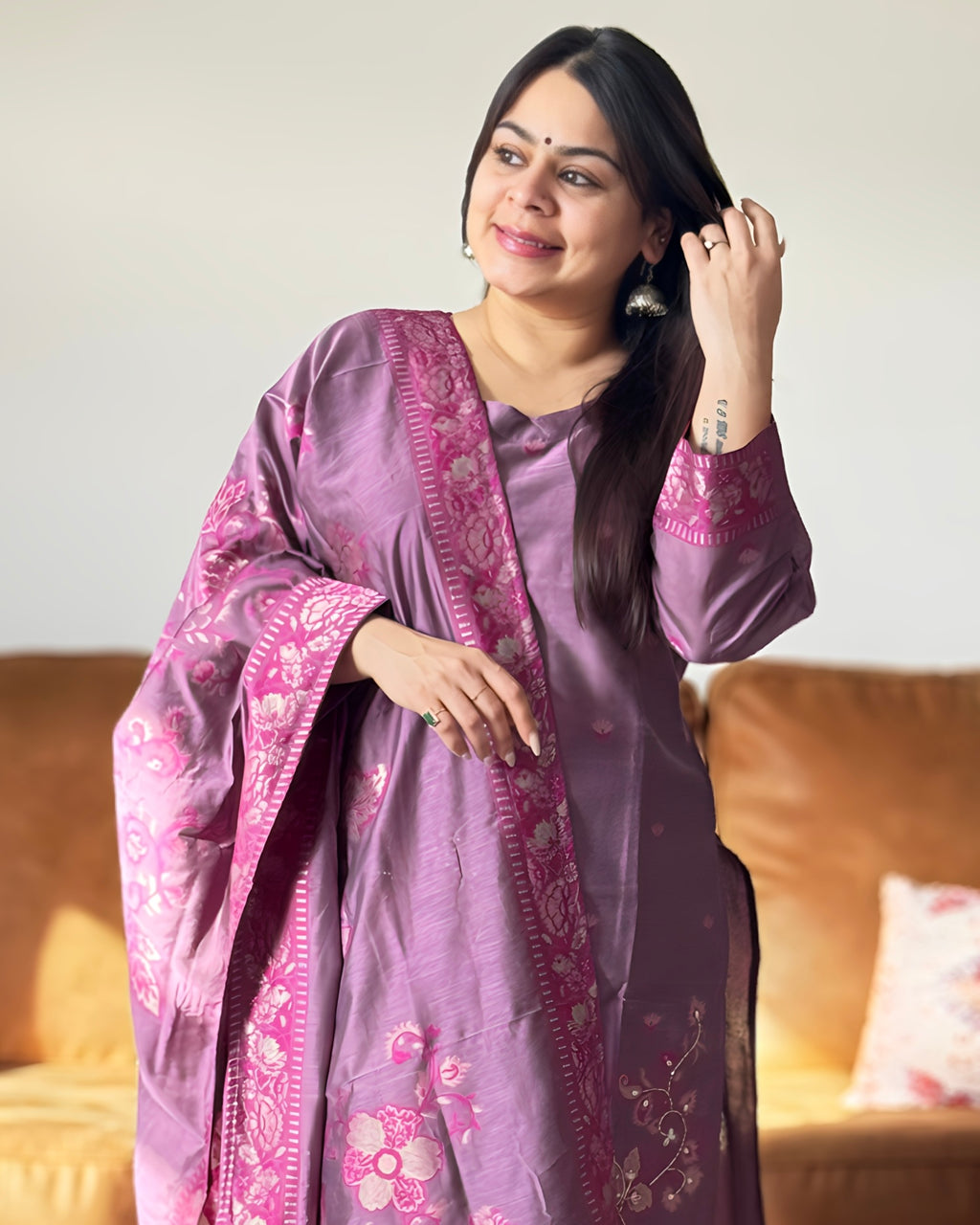 Woman wearing a purple traditional outfit with floral patterns in a room.