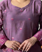 Purple traditional outfit with pink floral patterns and jewelry.