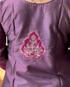 Purple garment with pink and white floral embroidery on a plain background
