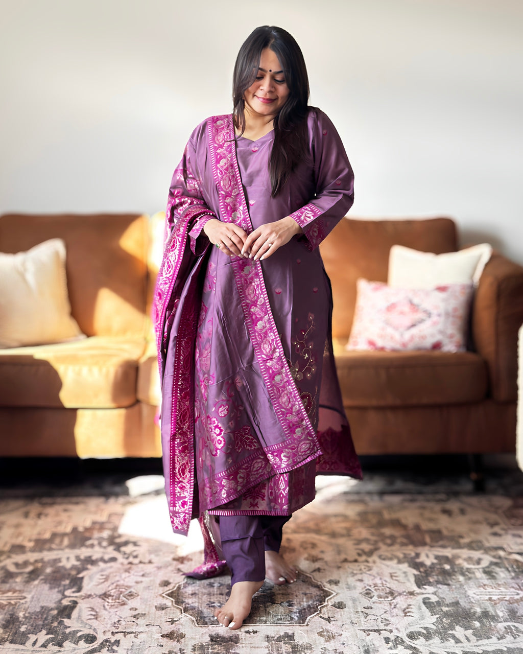 Woman in a purple traditional outfit standing in a living room.