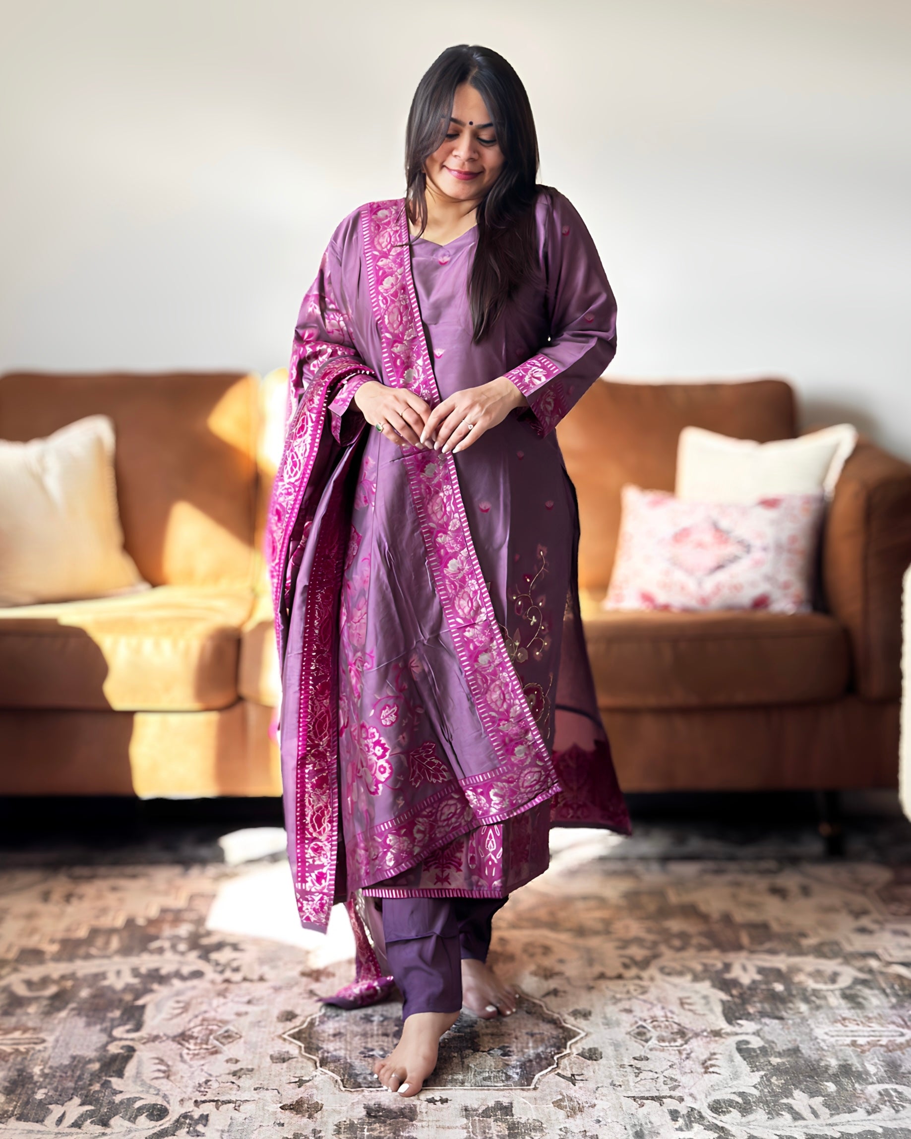 Woman in a purple traditional outfit standing in a living room.
