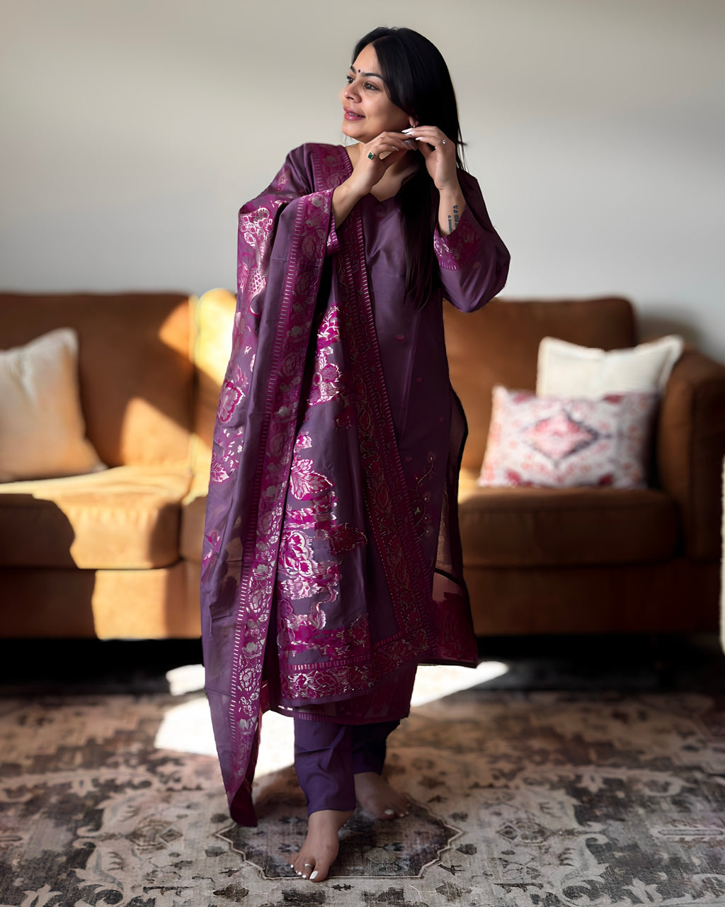 Woman in a purple traditional outfit standing in a living room.
