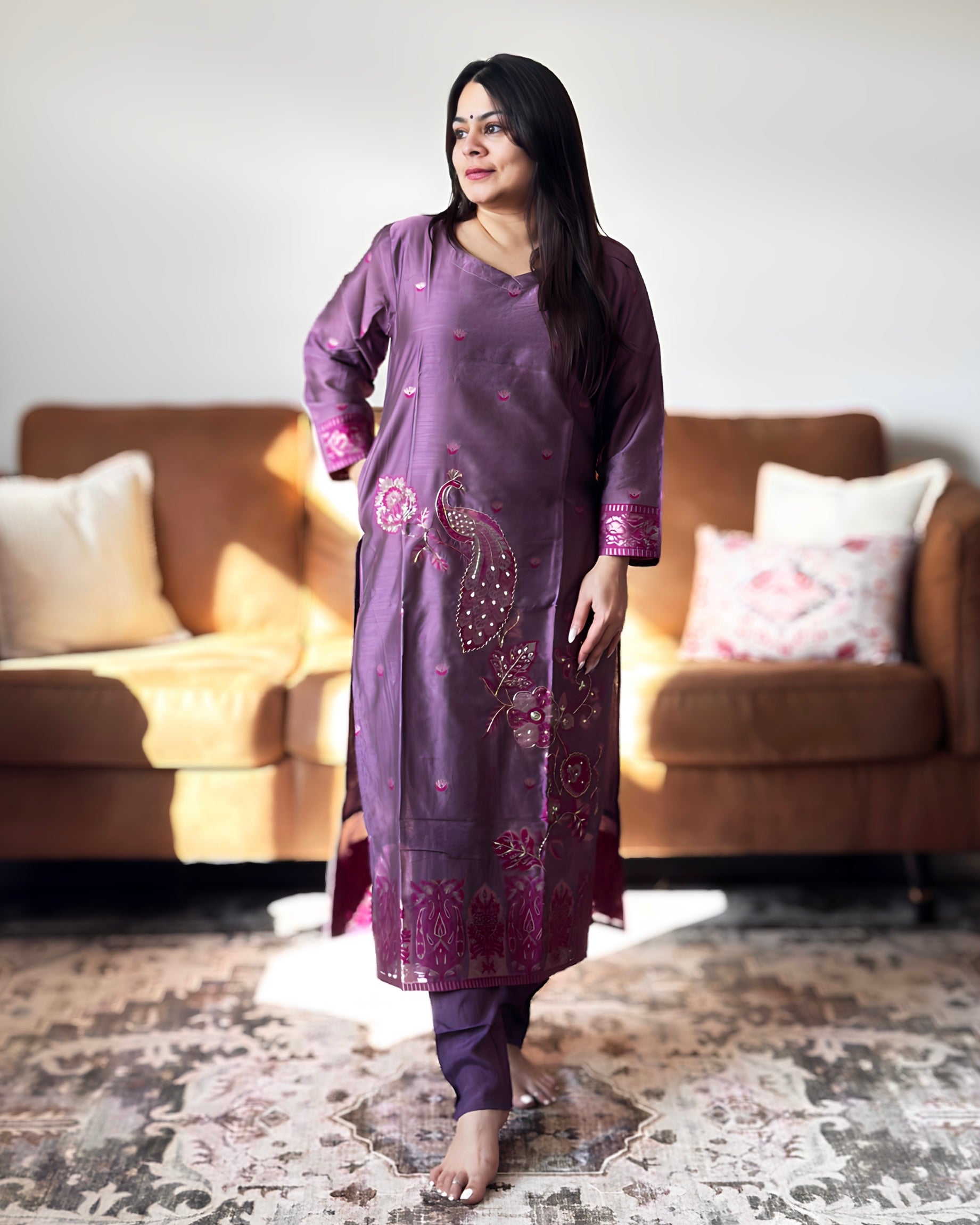 Woman wearing a purple traditional outfit with floral patterns in a living room setting.