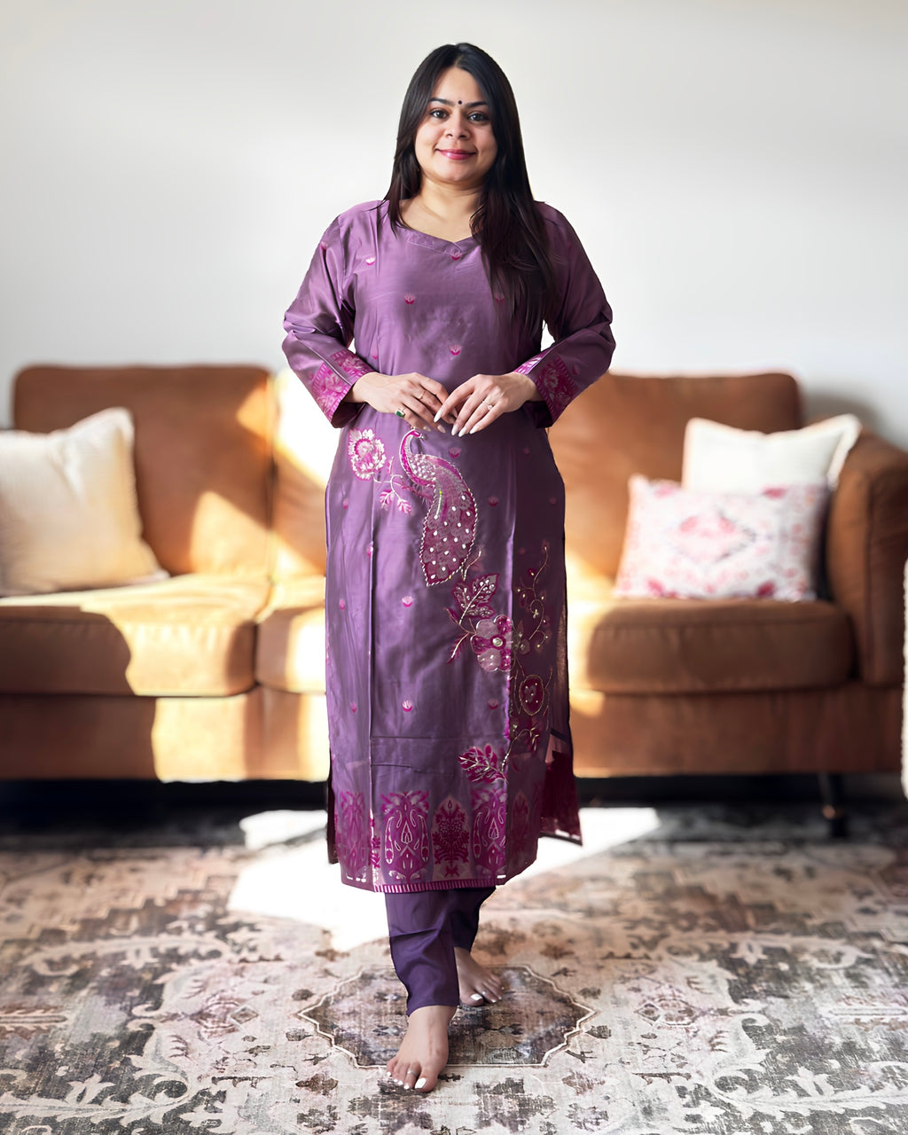 Woman in a purple traditional outfit standing in a living room.