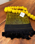 Green and black scarf with yellow pom-pom trim on a wooden surface