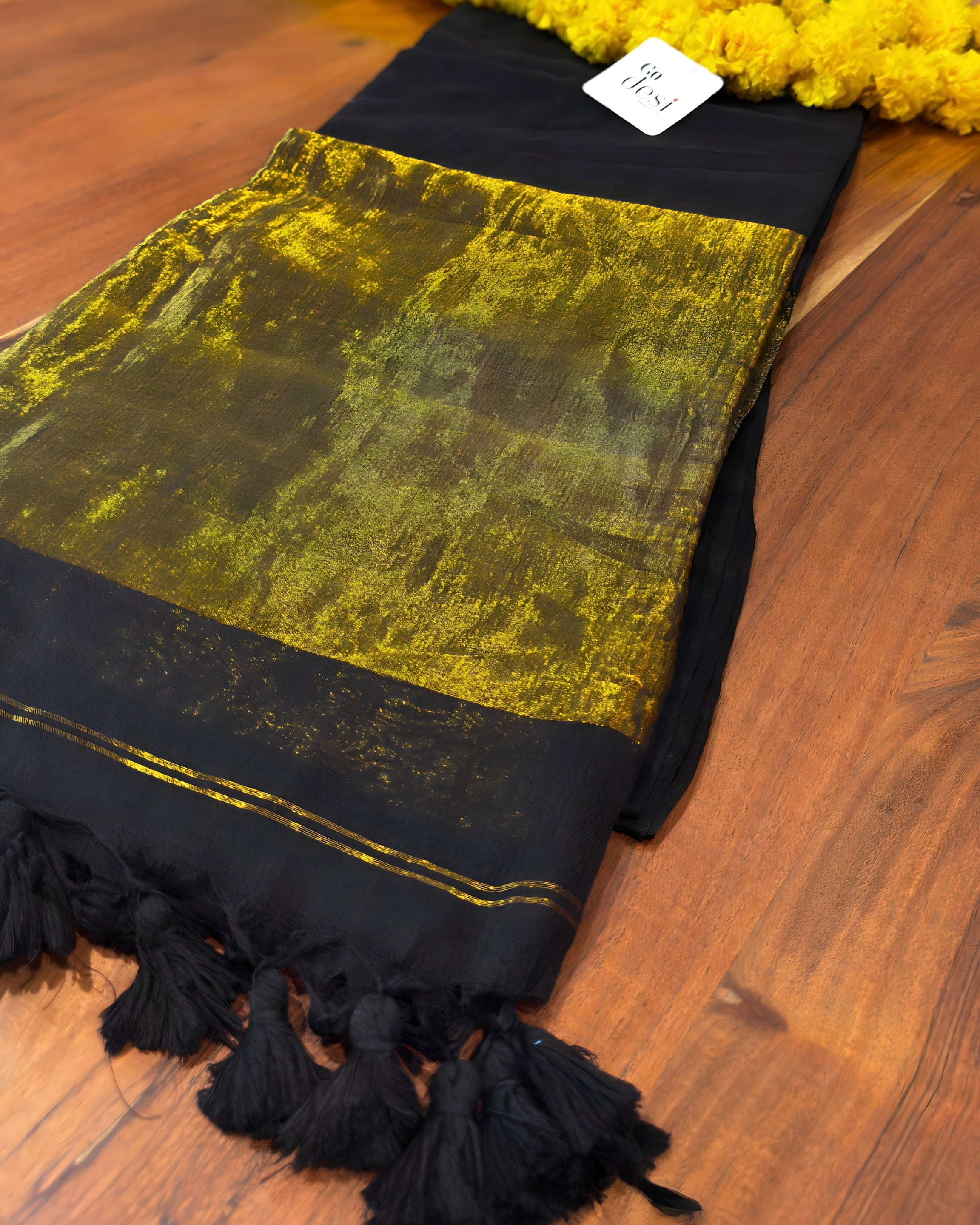 Black and gold scarf with tassels on a wooden surface