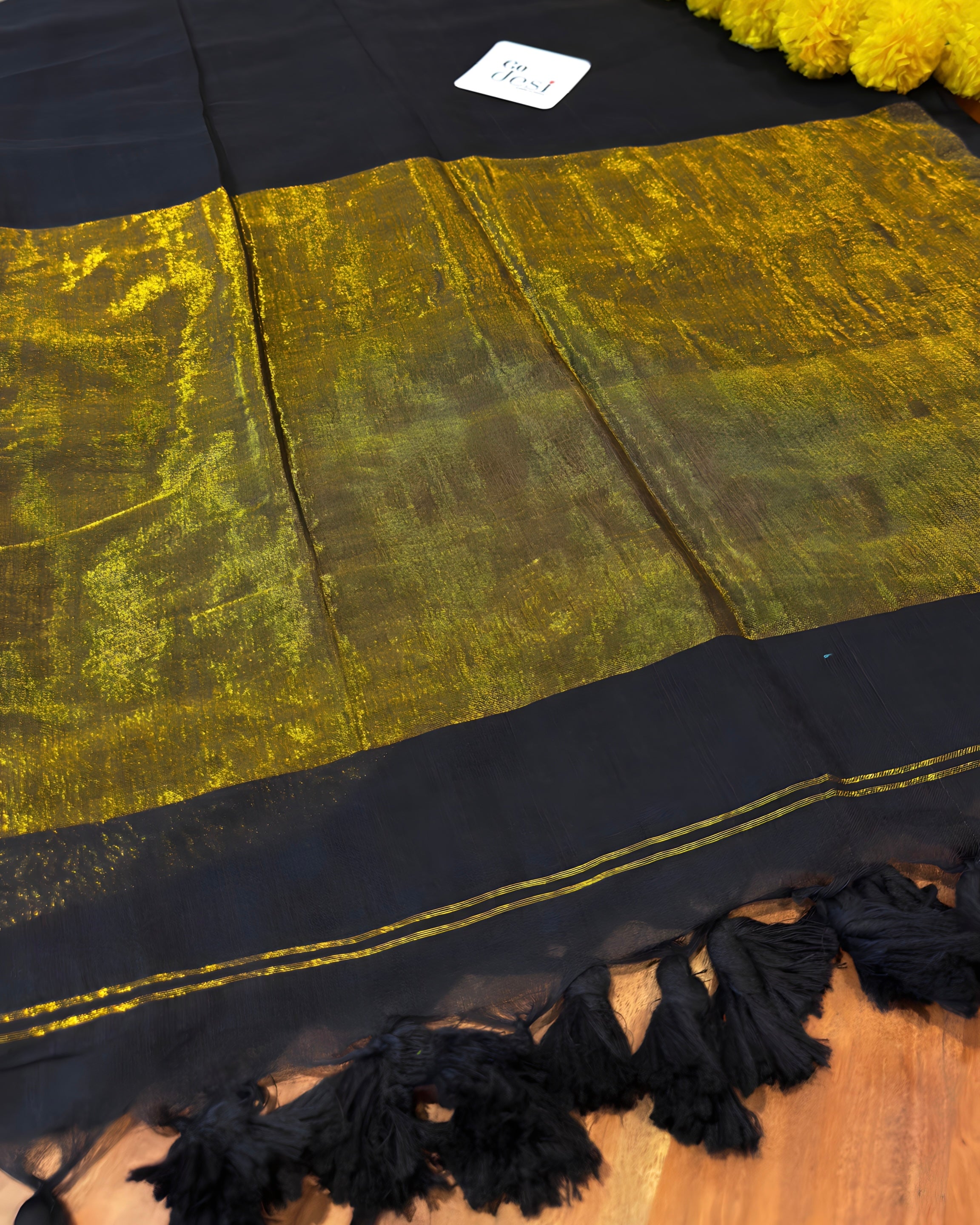Black and gold fabric with tassels on a wooden surface