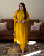 Woman in a yellow traditional outfit standing in a living room.