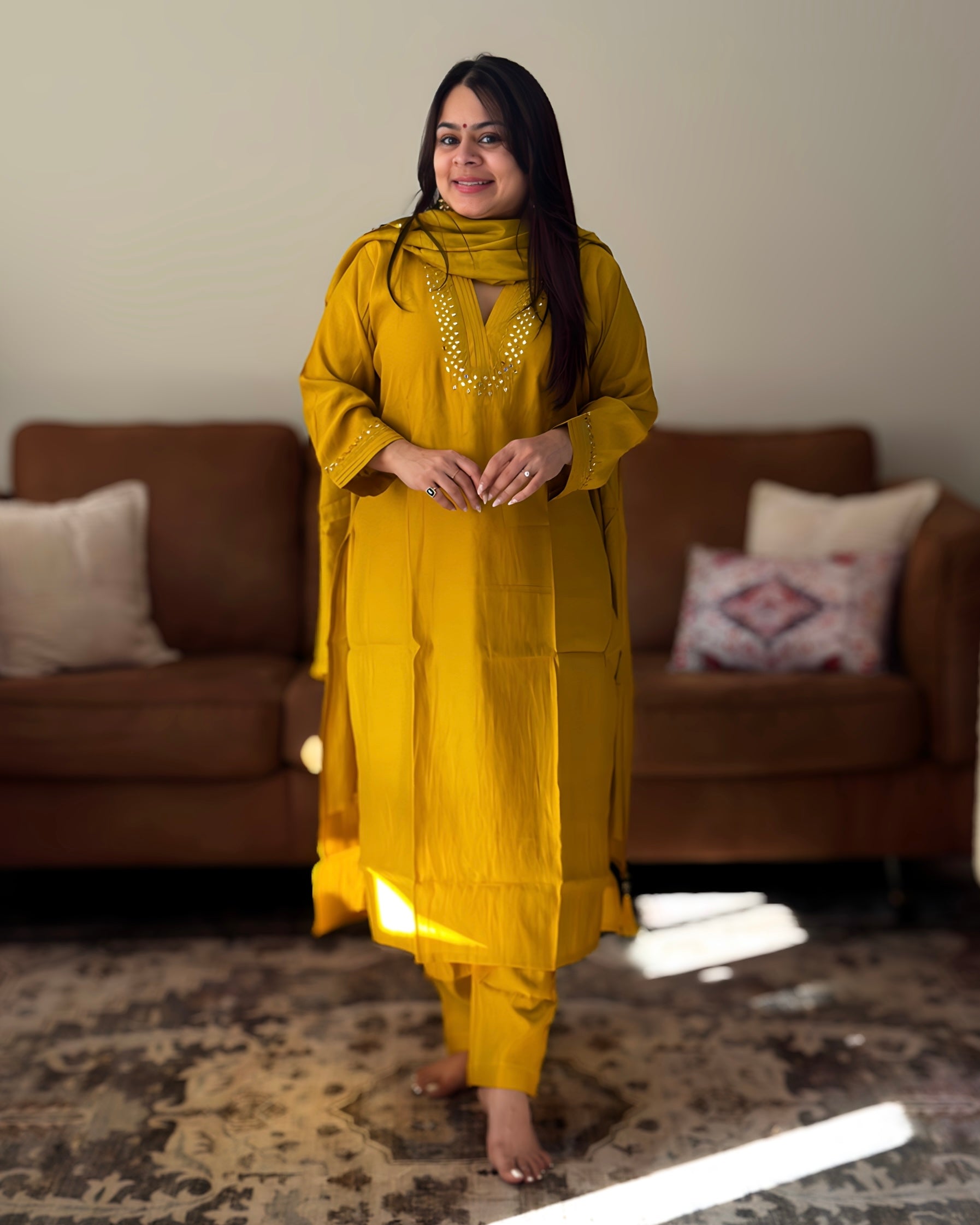 Woman in a yellow traditional outfit standing in a living room.