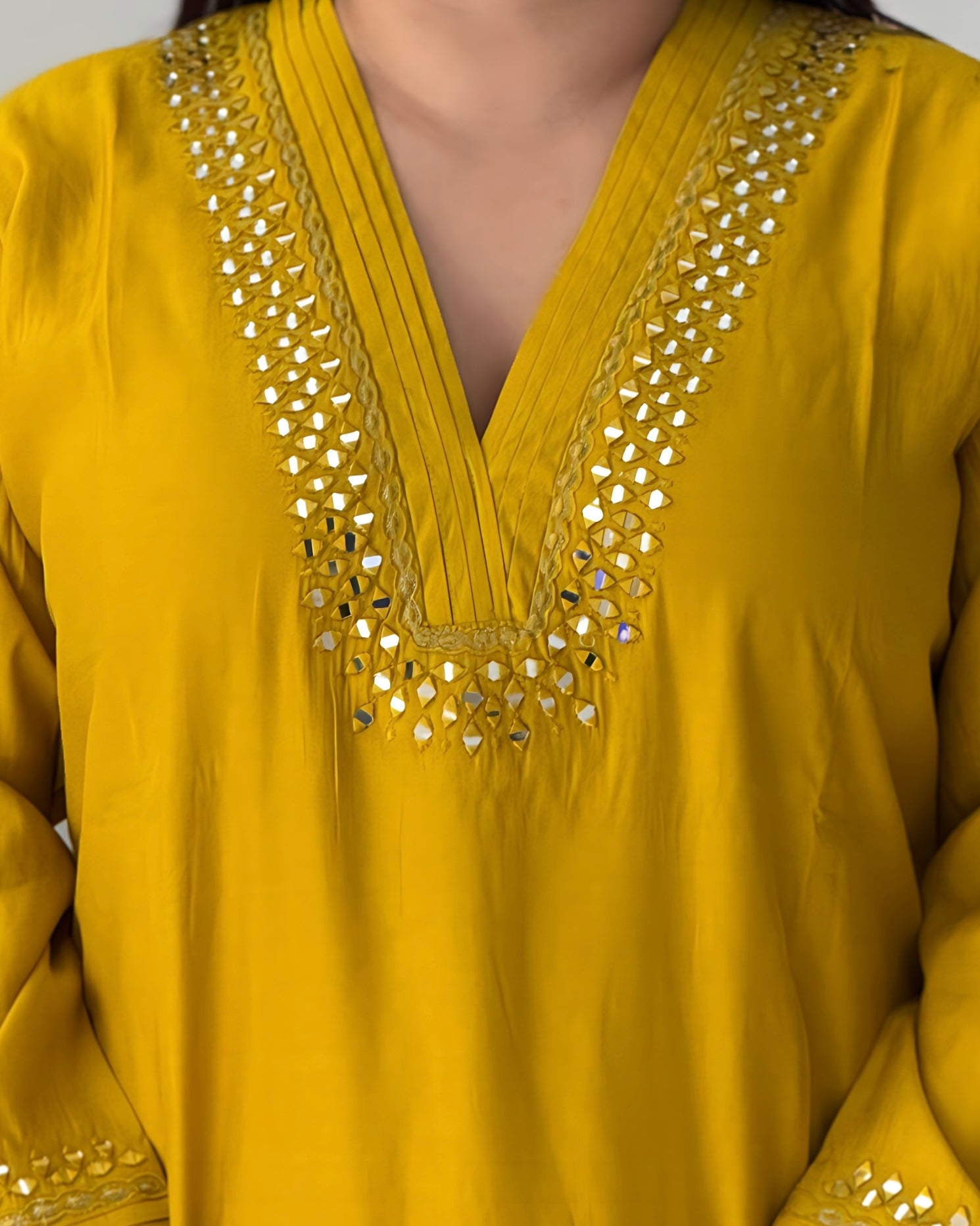 Yellow top with intricate mirror work on a plain background