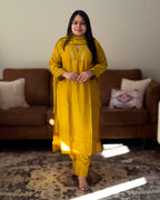 Woman in a yellow traditional outfit standing in a living room.
