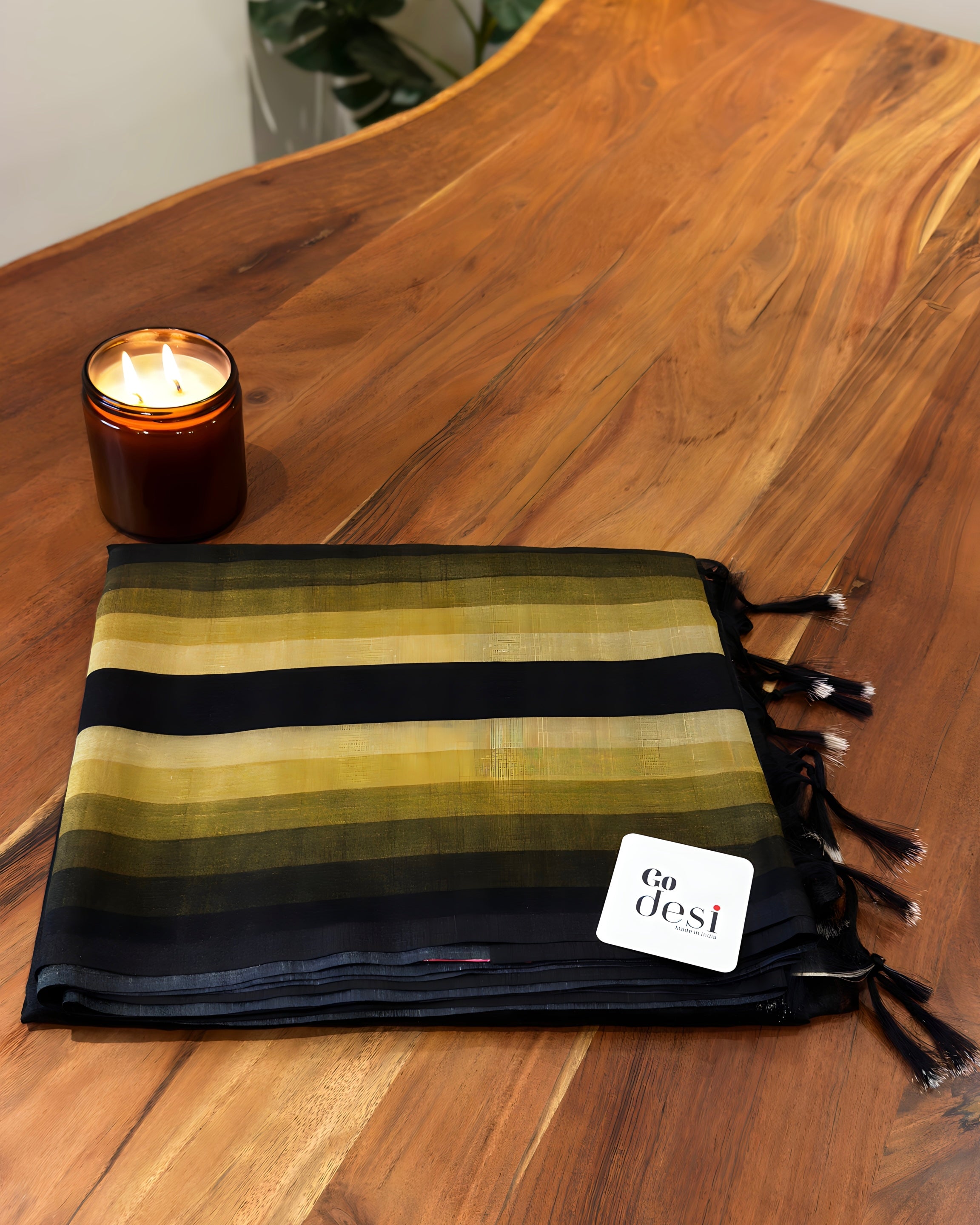 Striped blanket with tassels on a wooden surface next to a candle