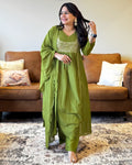 Woman in a green traditional outfit standing in a living room.