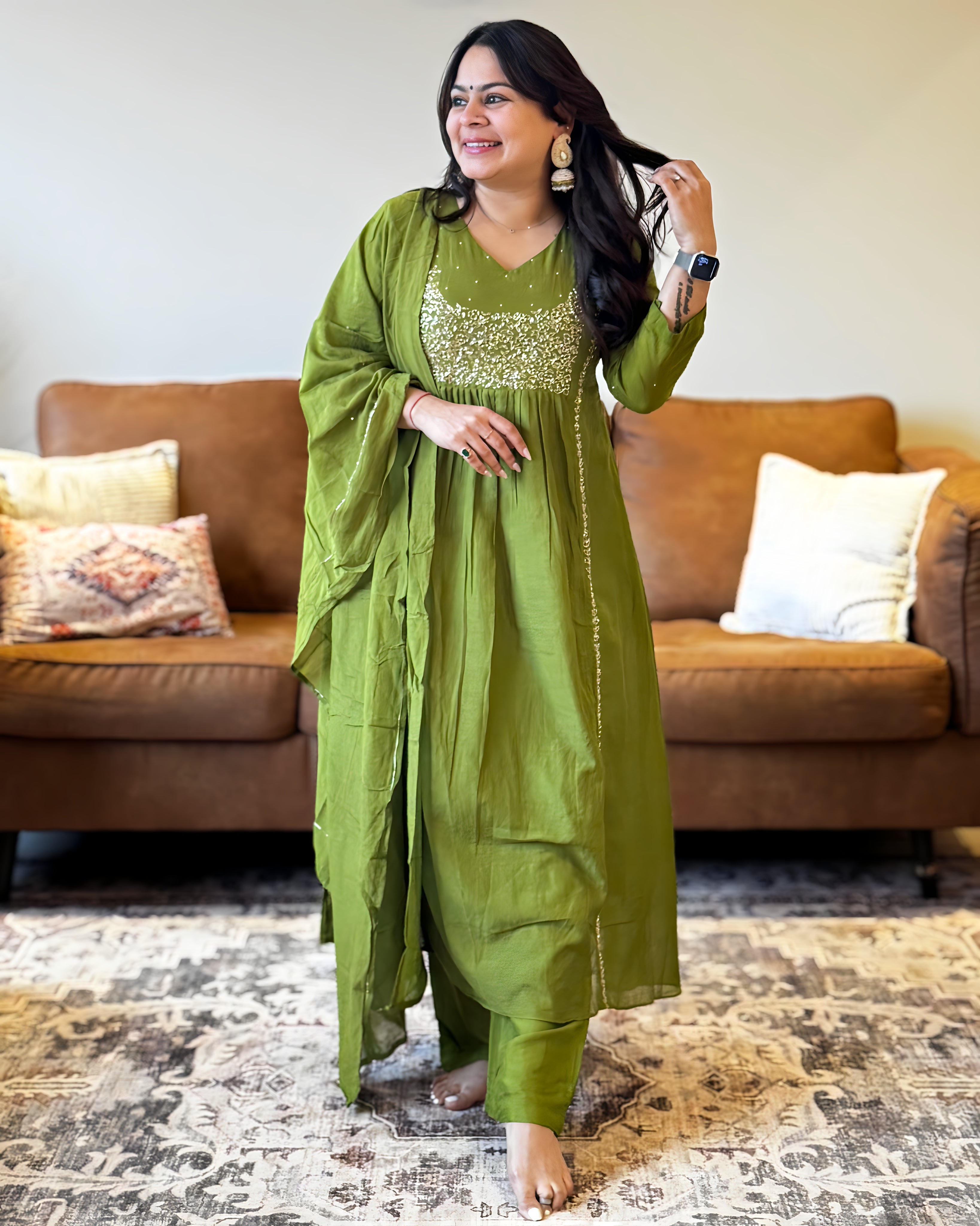 Woman in a green traditional outfit standing in a living room.