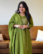 Woman in a green traditional outfit standing in a living room.