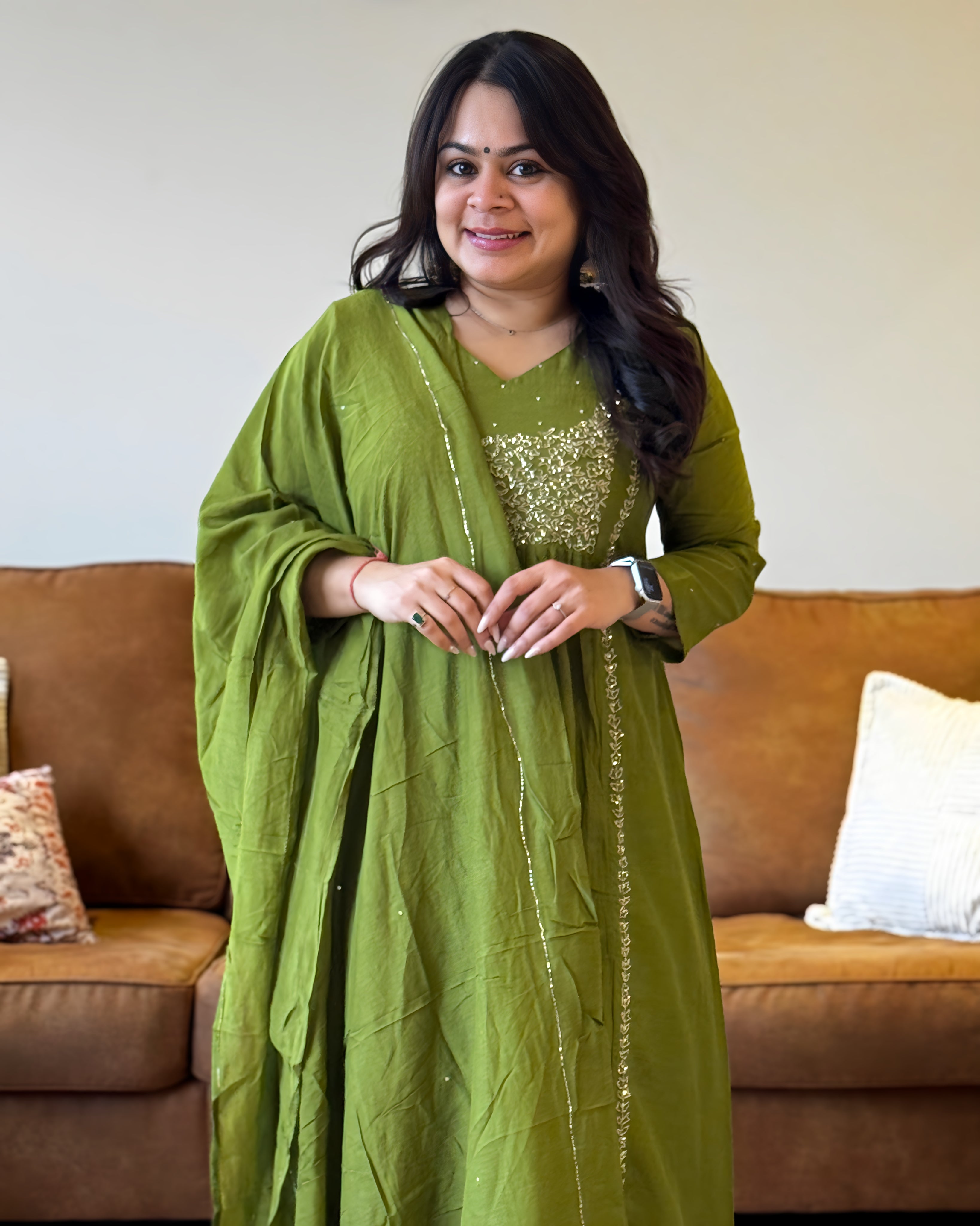 Woman in a green traditional outfit standing in a living room.