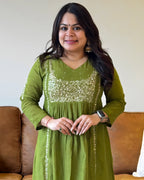 Woman wearing a green dress with sequin details in a home setting.