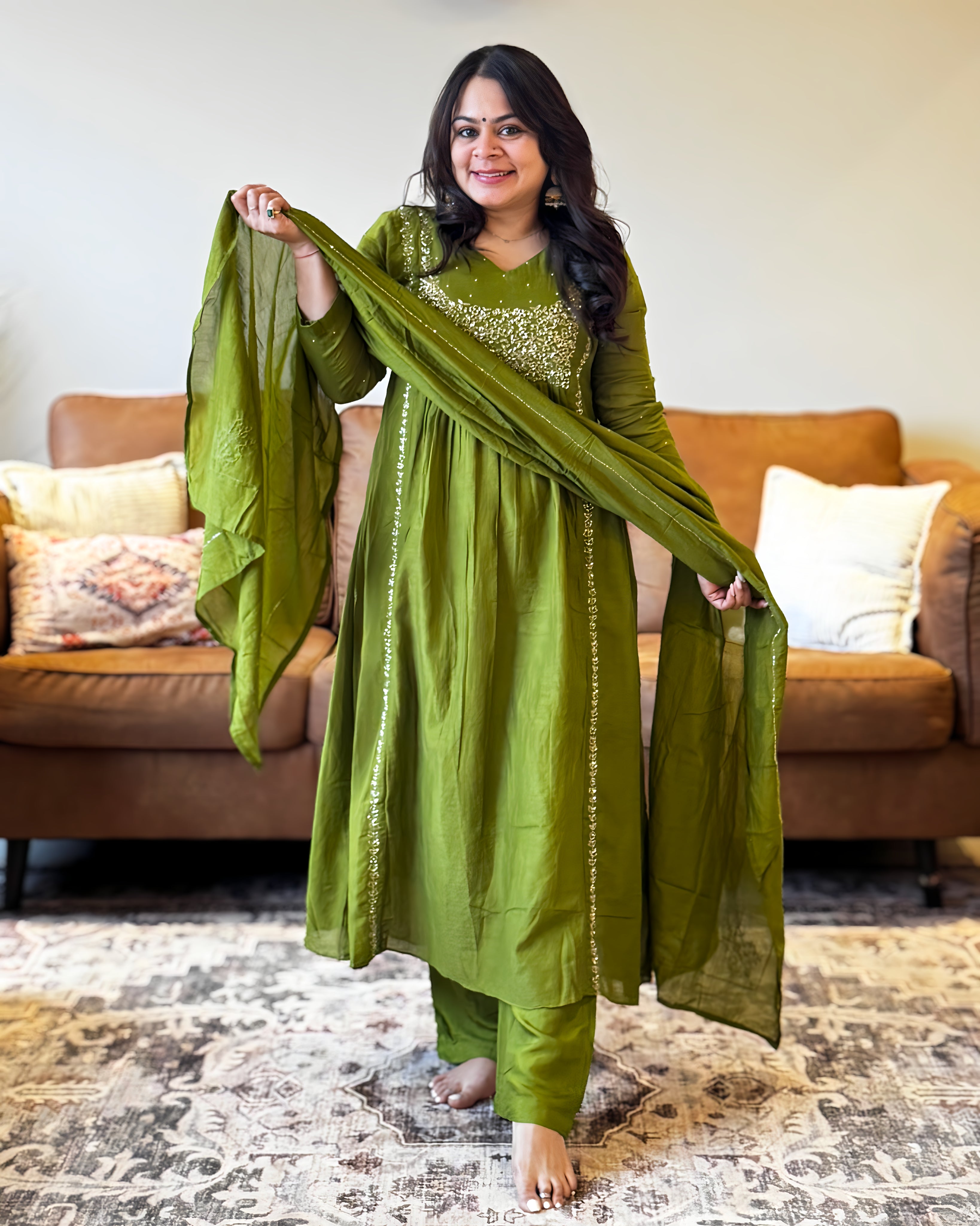 Woman in a green traditional outfit standing in a living room.