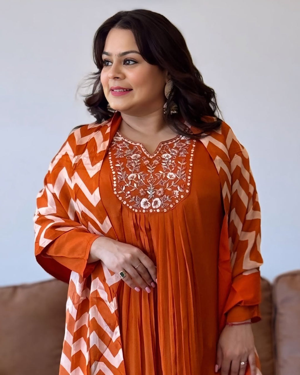 Woman wearing an orange and white traditional outfit with a chevron pattern.