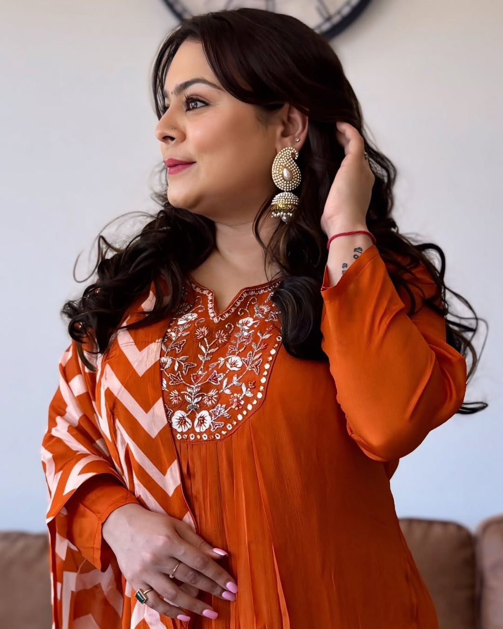 Woman wearing an orange and white embroidered dress with a blurred background