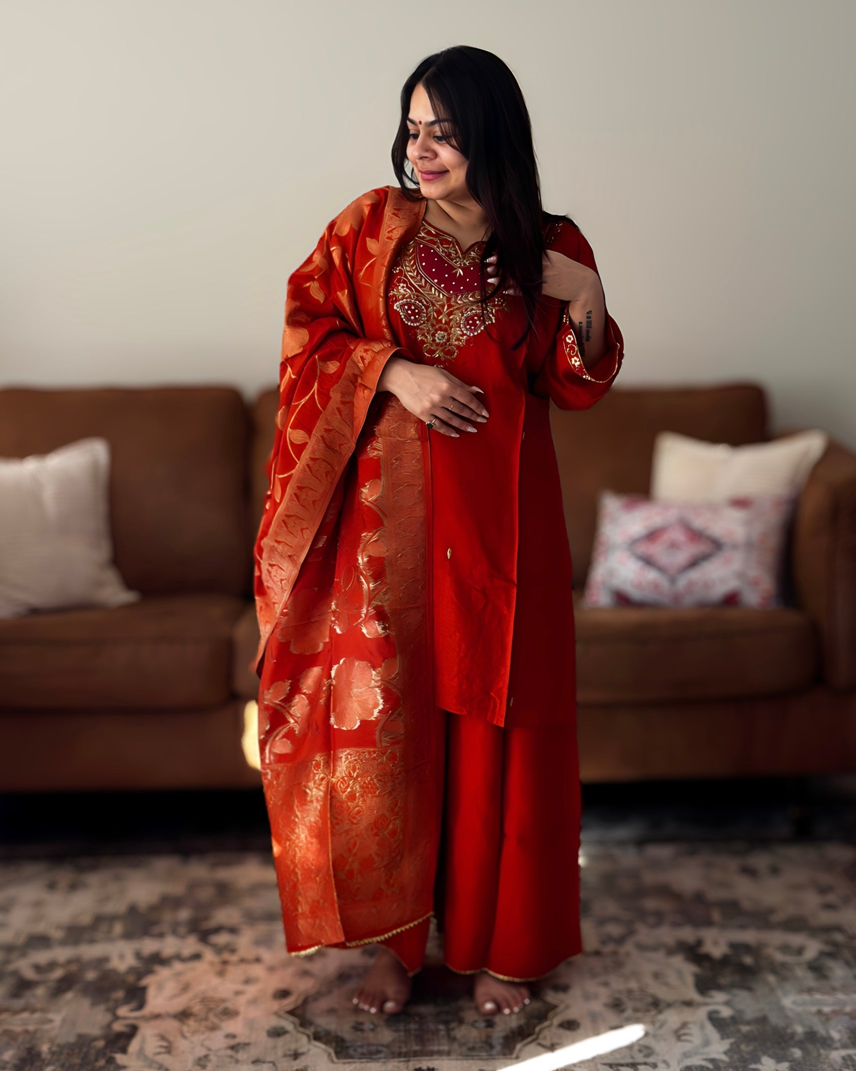 Woman in a red traditional outfit standing in a living room.